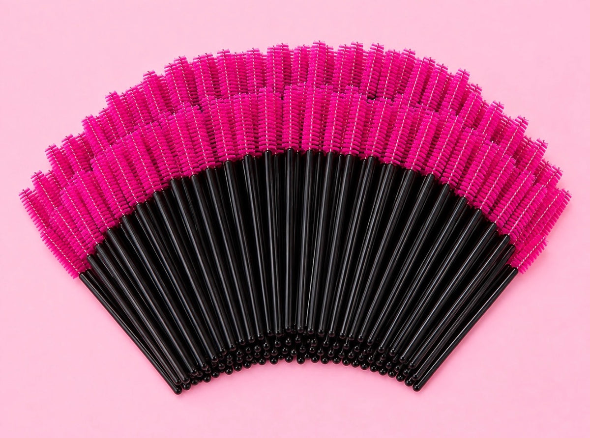A fan arrangement of black and hot pink makeup spoolie brushes on a solid pink background.100 or 300 pcs | Disposable Lash Spoolies for Eyelash Extensions Bratty Beauty XO