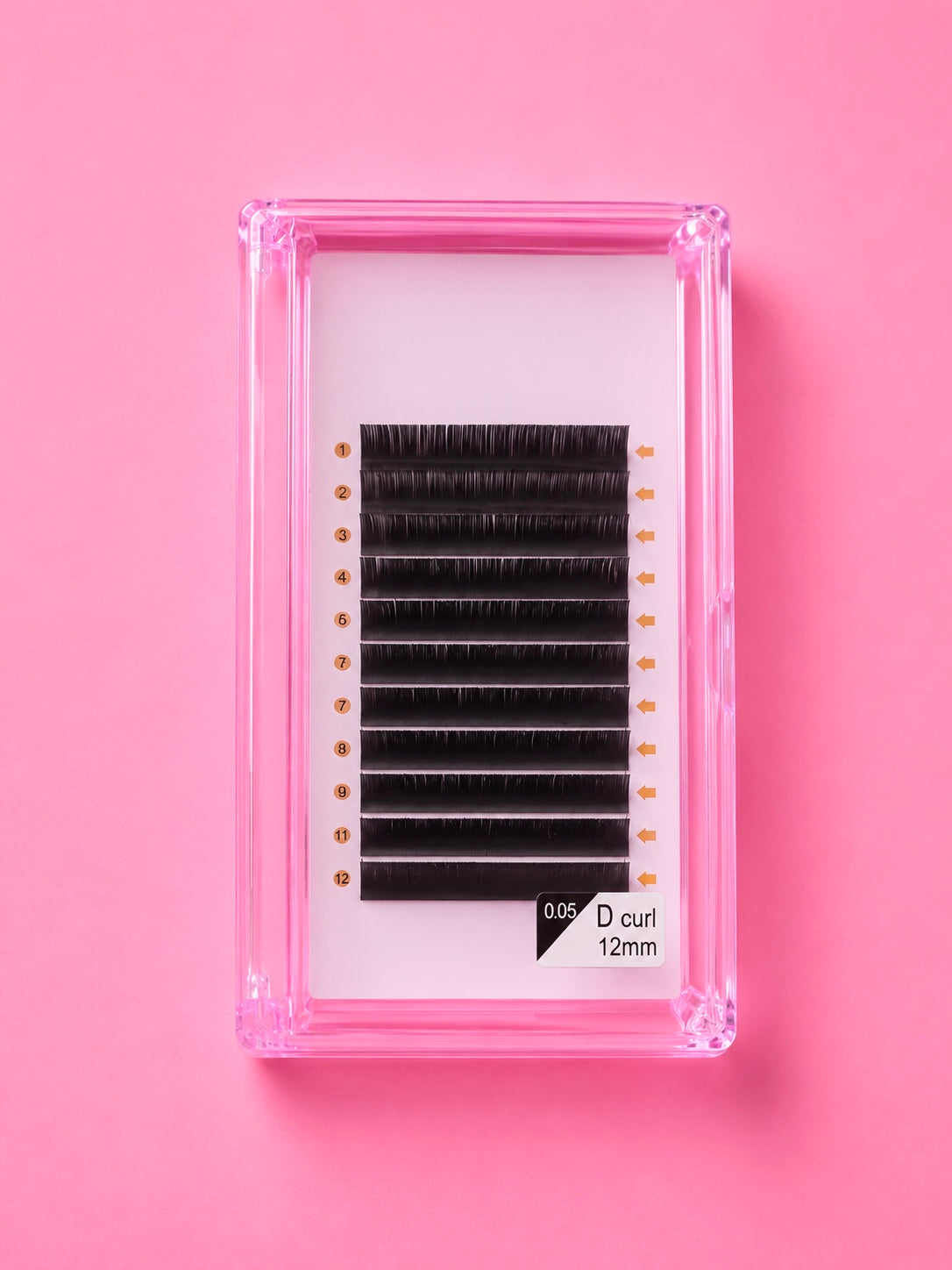 A pack of black false eyelash clusters in a clear pink plastic tray, displayed on a solid pink background. The label on the bottom right reads 0.05 12mm Bratty Beauty XO Matte Black 0.05 D Curl 12mm Lash Extension Tray