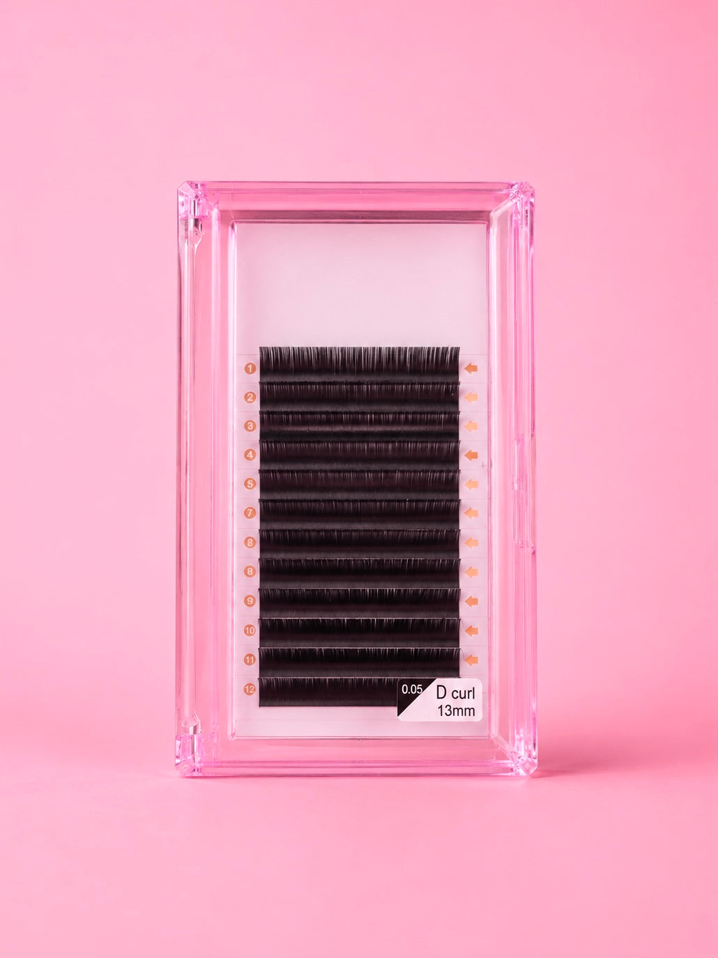 A pack of black false eyelashes with a D curl and 13 mm length, presented in a clear pink plastic case on a solid pink background.Bratty Beauty XO Matte Black 0.05 D Curl 13mm Lash Extension Tray 