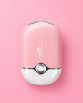 A pink and white handheld electric facial cleansing brush with a Pokéball-inspired design, featuring a silver button and LED light bar on top. Pink or Black Portable Mini Lash Fan for Eyelash Extensions Bratty Beauty XO