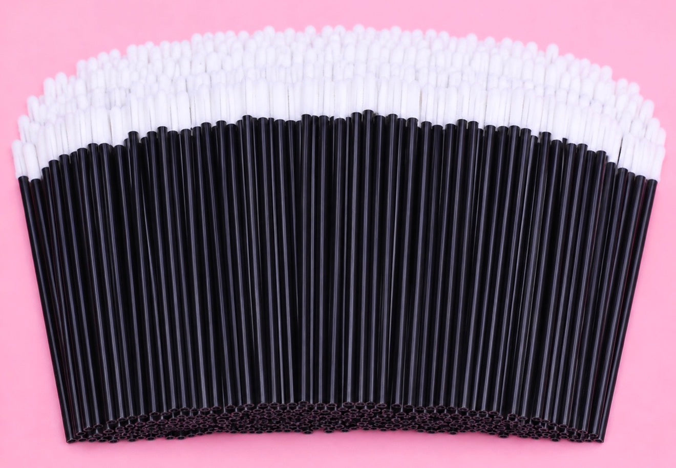 A large quantity of disposable paper straws arranged in a semi-circle on a solid pink background, featuring black straws with white tips. Pink or Black Disposable Lip Brushes/ Lip Wands | 500 or 700 pcs