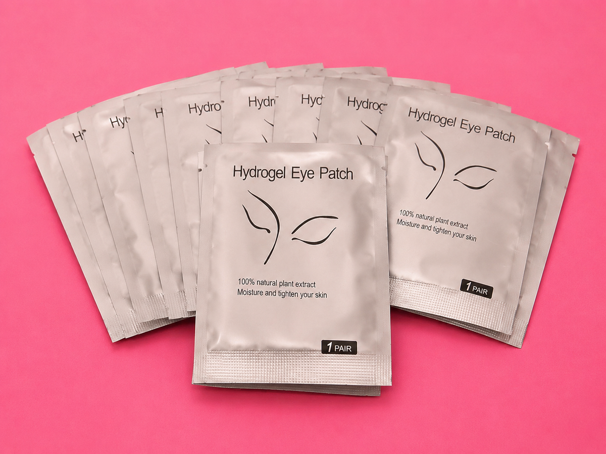 Five silver foil packets of Hydrogel Eye Patch arranged in a fan shape on a solid pink background.100 pairs Of Hydrogel Under Eye Patches Bratty Beauty XO