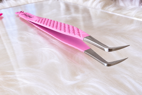 Pink and silver curved tweezers with a textured grip handle, resting on a white faux fur surface.Big Boss Fanning Tweezer, bratty beauty xo volume lash tweezer